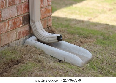 Downspout Emptying Rain Water  Into A Splash Block, Concrete Splash Block On Grass For Drain Spout