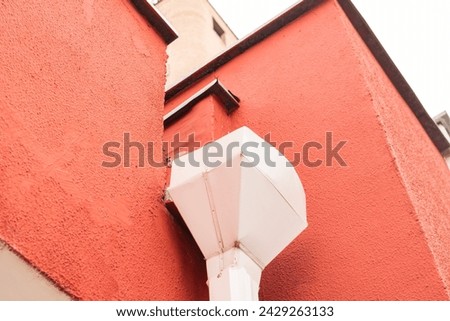 Downspout on the wall of a red building close up