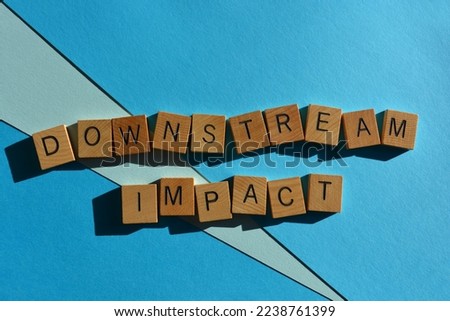 Downstream Impact, business buzzword phrase in wooden alphabet letters isolated on blue background