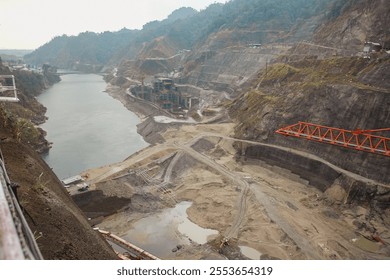 Downstream view of an ongoing construction work of a hydroelectric dam over a torrential hill stream in the Himalayas. 