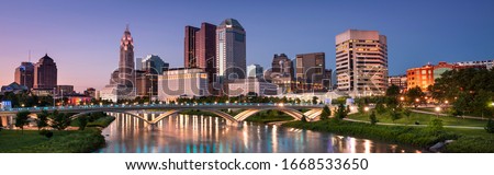 Downtown cityscape panorama looking over the Scioto River and the Discovery Bridge along the Riverfront Park in the city of Columbus Ohio USA