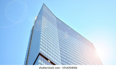 Downtown corporate business district architecture. Glass reflective office buildings against blue sky and sun light. Economy, finances, business activity concept. Rising sun on the horizon. - Powered by Shutterstock