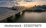 Downtown district of Cincinnati city in Ohio, USA at sunset with driving cars traffic on Daniel Carter Beard Bridge and brightly illuminated high skyscraper buildings. American travel destination