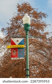 DOWNTOWN LAFAYETTE sign in the form of seal and flag on a street lamp in downtown Lafayette, Louisiana