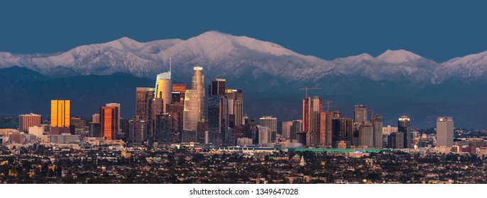 Downtown Los Angeles Skyline With Snow Capped Mountains Behind At Twilight