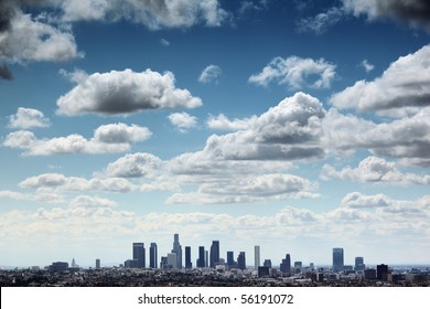 Downtown Los Angeles skyline under blue sky with scenic fluffy clouds.