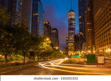 Downtown Manhattan Street View At Dawn Featuring Car Lights On The Foreground And Buildings On The Background