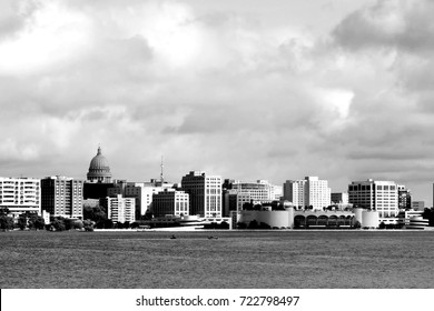Downtown skyline of Madison,the capital city of Wisconsin,USA.Morning view with State Capitol and official buildings in sunlight against beautiful cloudy sky and lake water as seen across lake Monona.