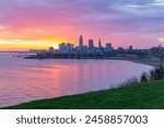 Downtown skyline silhouette behind bay with pink and yellow sunrise