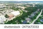 Downtown Southlake Texas mixed use development with large shopping center busy parking lot, residential neighborhood upscale houses swimming pool, municipal area with water tower, aerial view. USA