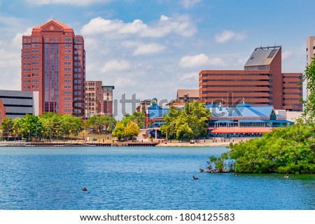 Downtown Toledo Ohio is filled with multi colored architecture that sits alongside the Maumee River. Ducks float in the water and sit on the island.