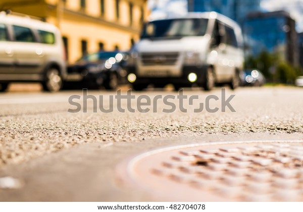 In the downtown, the\
van passing by on the street. Close up view of a hatch at the level\
of the asphalt