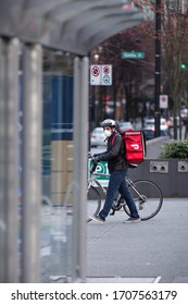 DOWNTOWN VANCOUVER, BC, CANADA - APR 01, 2020: A DoorDash Food Delivery Worker Wearing A Medical Facemask Amid The Covid 19 Pandemic.