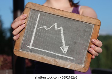 Downward Trend Graph Drawn With Chalk On Writing Slate Shown By Young Female