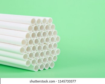 Dozens of biodegradable eco-friendly paper straws bundled together facing forward on a green background with copy space. Many cities are now banning single use plastic straws.