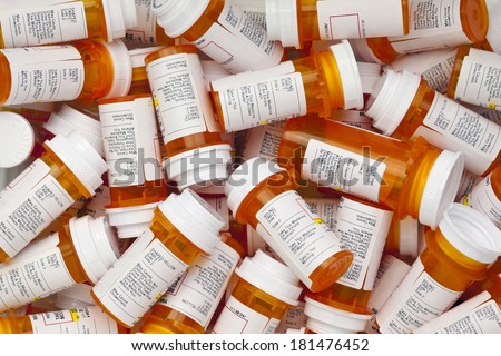 Dozens of prescription medicine bottles in a jumble. This collection of pill bottles is symbolic of the many medications senior adults and chronically ill people take. 
