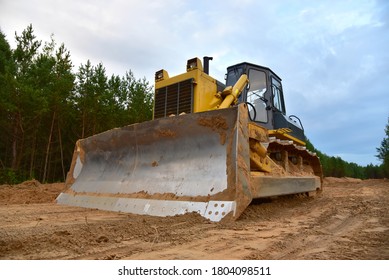 Dozer during clearing forest for construction new road . Yellow Bulldozer at forestry work Earth-moving equipment at road work, land clearing, grading, pool excavation, utility trenching