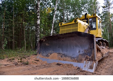 Dozer during clearing forest for construction new road . Yellow Bulldozer at forestry work Earth-moving equipment at road work, land clearing, grading, pool excavation, utility trenching