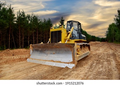 Dozer during clearing forest for construction new road. Bulldozer at forestry work on sunset background. Earth-moving equipment at road work, land clearing, grading, pool excavation, utility trenching - Shutterstock ID 1915212076