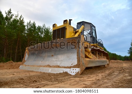 Dozer during clearing forest for construction new road . Yellow Bulldozer at forestry work Earth-moving equipment at road work, land clearing, grading, pool excavation, utility trenching