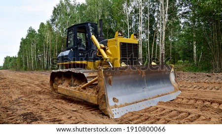 Dozer during clearing forest for construction new road . Yellow Bulldozer at forestry work Earth-moving equipment at road work, land clearing, grading, pool excavation, utility trenching