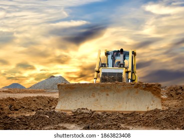 Dozer on earthmoving at construction site on awesome sunset background. Construction machinery and earthmoving equipment on groundwork. Bulldozer leveling ground for new road construction