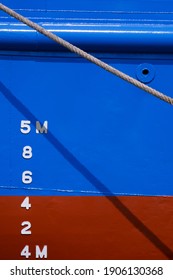 Draft Mark Numbers On Side Of Blue And Red Rust Proof Vessel Hull Behind The Old Giant Fiber Rope In Vertical Frame