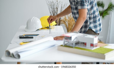 Draftsman is designing house plan, model houses and house plans with a safety helmet on the desk.