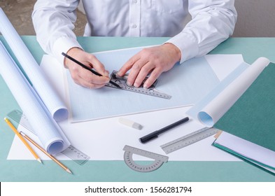 Draftsman using t-square and pencil for drafting on the graph paper. Professional constructor`s workplace