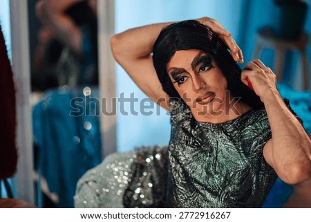Drag queen applying makeup and brushing wig, getting ready for a performance, celebrating gender expression and artistic transformation