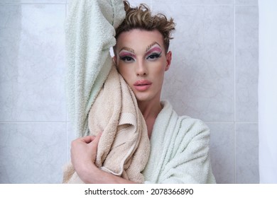 Drag Queen Person Wearing Bathrobe Posing Looking At Camera In A Bathroom.