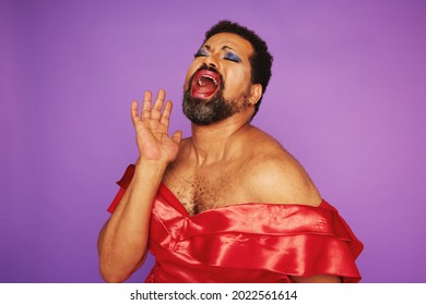 Drag queen singing in a theater. Man with beard wearing makeup and female dress giving a theatrical performance. - Shutterstock ID 2022561614