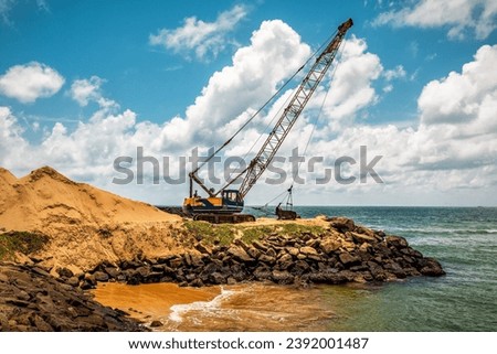 Dragline excavator working digging on the sea beach. Industrial theme