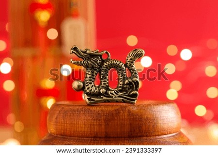Dragon figurine against blurred lights on red background, closeup. Chinese New Year celebration