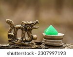 A dragon figurine with coins and a pyramid made of mineral is a financial symbol.