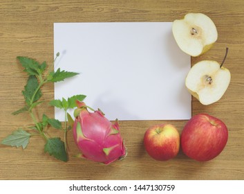 Dragon Fruit, Purple, Yellow Wheelbarrow Yellow-red Apples On White Paper, Leaves, Wood Background, Brown Pattern