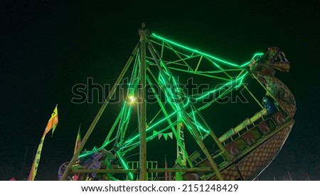 Dragon swing boats with green neon lights at night