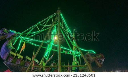 Dragon swing boats with green neon lights at night