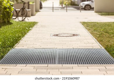 Drain Grating And Gutters For Drainage Of Rainwater And Paving Slabs On Cobblestone Sidewalk. Modern Footpath, Sidewalk In Urban Yard. 