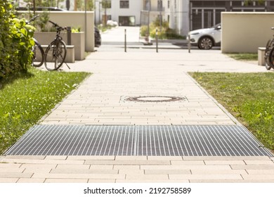 Drain Grating And Gutters For Drainage Of Rainwater And Paving Slabs On Cobblestone Sidewalk. Modern Footpath, Sidewalk In Urban Yard. 