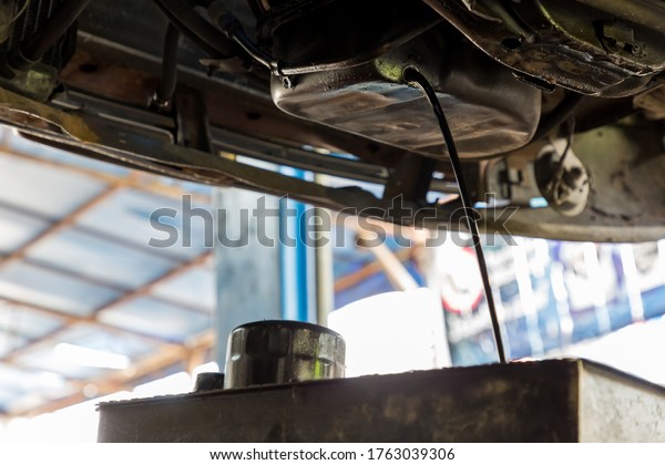 Drain the old oil from the engine through the drain\
plug. Changing the oil in a car engine. discharge of waste oil from\
motor car. Draining used diesel engine power from an oil pan into a\
container 