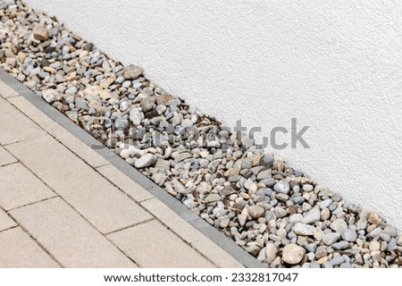 Drain Pebbles installation Along Wall House and Paving Stones of Pavement. Drainage System Along Wall Building Facade. Drain Floor