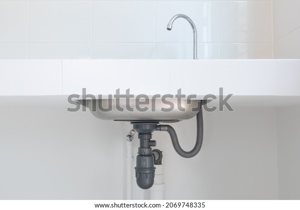 Drain pipe or sewer under kitchen sink. Pvc\
plastic pipe and\
 flexible supply tube connection to stainless\
steel sink include faucet, trap for drain water and waste in\
drainage and plumbing\
system.