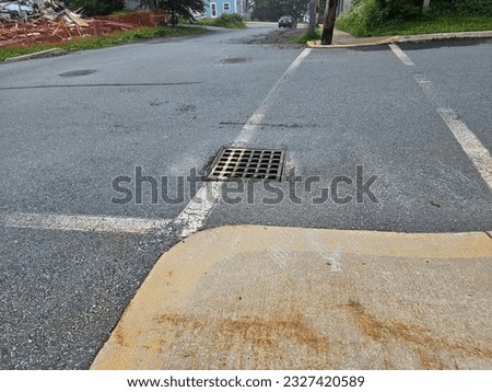 A drain vent in a crosswalk along a street.