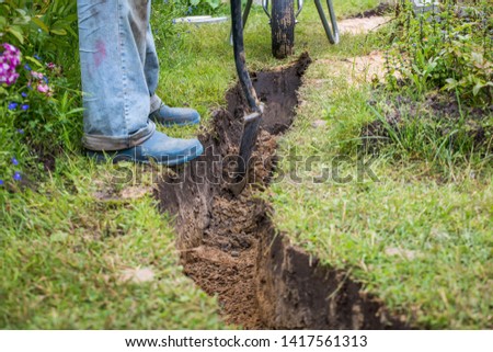 Drainage ditch. A man is digging a ditch. Laying a drainage pipe. Earthwork.

