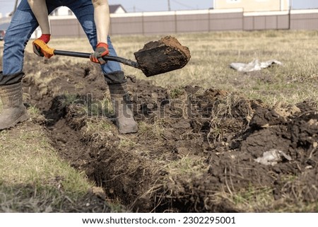 Drainage ditch. A man is digging a ditch. Laying a drainage pipe. Earthwork. A Worker digs soil with shovel. Stock foto © 