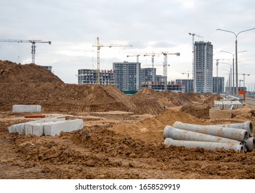 Drainage pipes at the large scale construction site against tower cranes. Installation of water main, sanitary sewer, storm drain systems. Renovation program, buildings industry background
