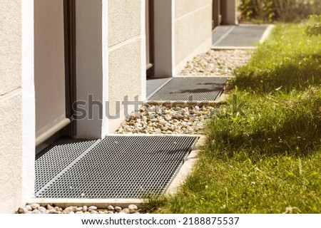 Drainage Surface around House. Drain for Water in front of Door. Pebbles for Water Drainage along House Wall. Drain Floor