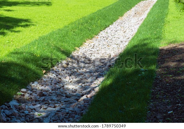 drainage, a drainage system in a Park area, a\
waterway overgrown with lawn and paved with stones, an Aqueduct\
between nature and the road. stone water drains in a grass garden\
field. Lawn and plant