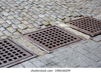 Drainage System Of Urban Infrastructure With An Iron Grating Of The Hatch Of The Stormwater System Of The Sidewalk From Granite Tiles Near The Road From The Paving Stones, Nobody.